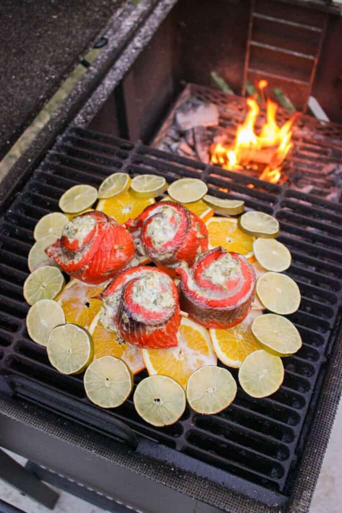 green chili salmon pinwheels on a citrus plank on the grill next to a fire