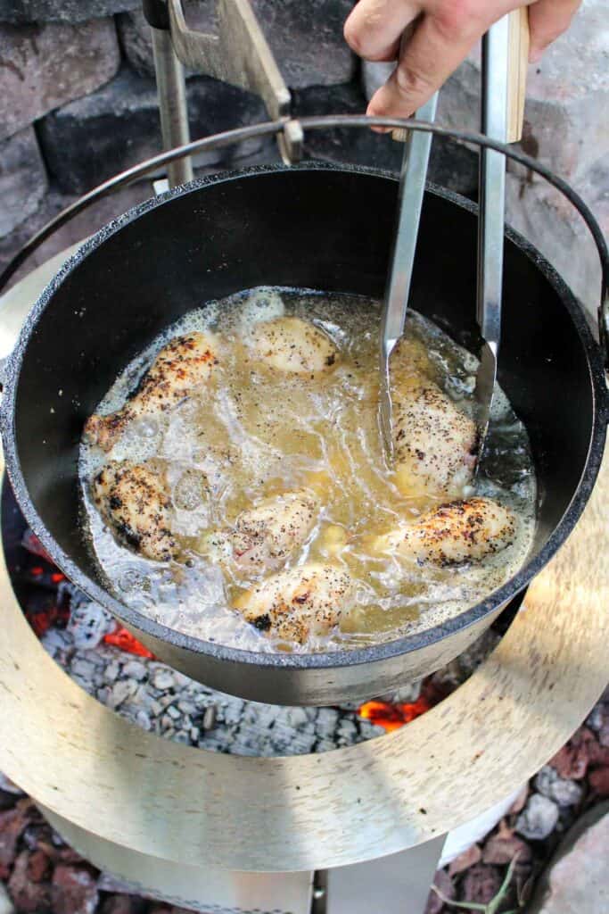 chicken being braised in a pot of broth