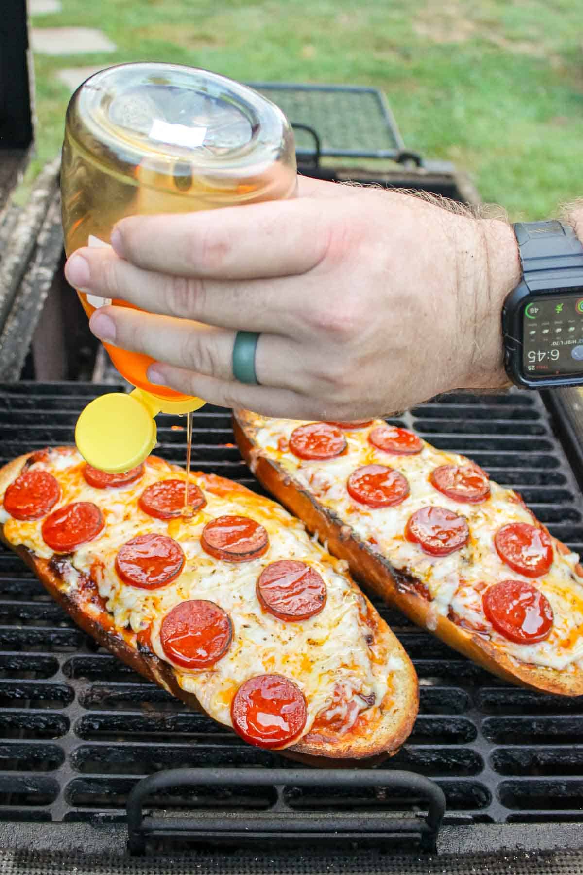 honey being drizzled over the top of finished pepperoni pizza bread