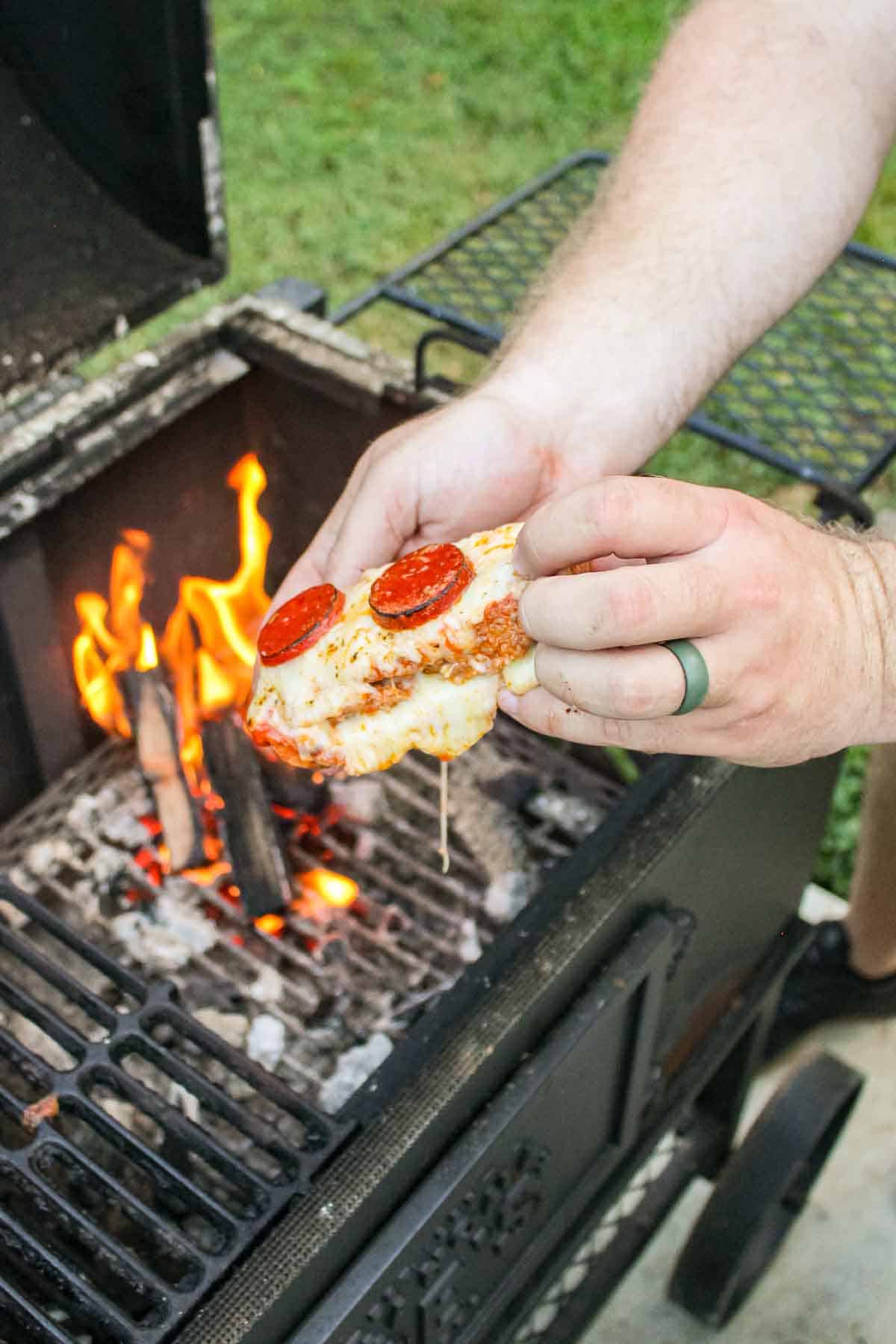 a partially eaten piece of pizza bread held over a grill