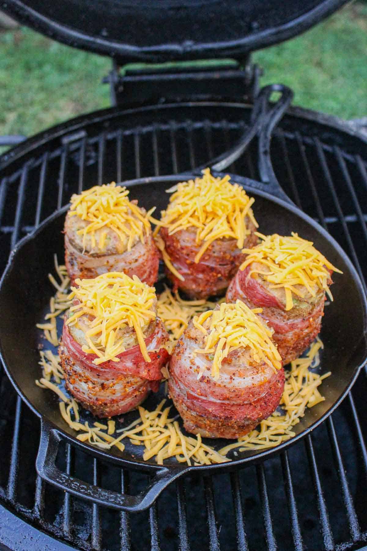 five bbq volcano potatoes topped with cheese in a skillet on the smoker