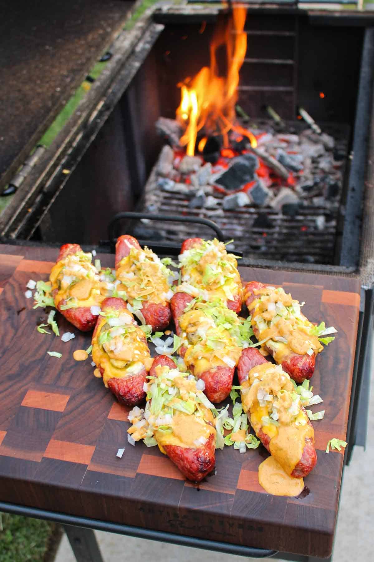 overhead of sausage poppers on a cutting board by a grill