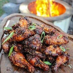 overhead of a platter filled with honey chili oil chicken wings next to a fire