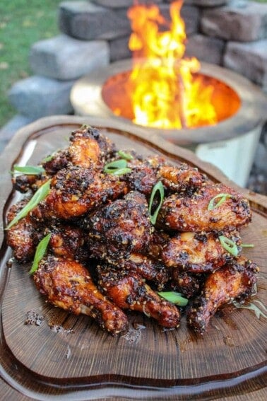 overhead of a platter filled with honey chili oil chicken wings next to a fire