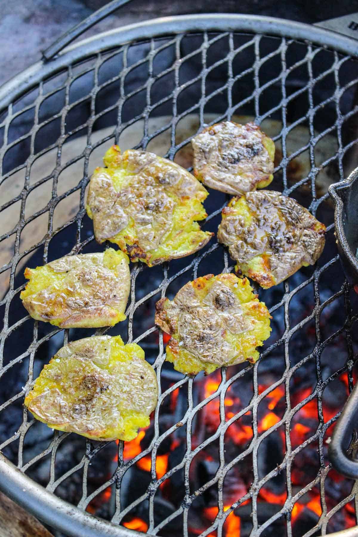 Crispy smashed potatoes on a grill basted with oil. 