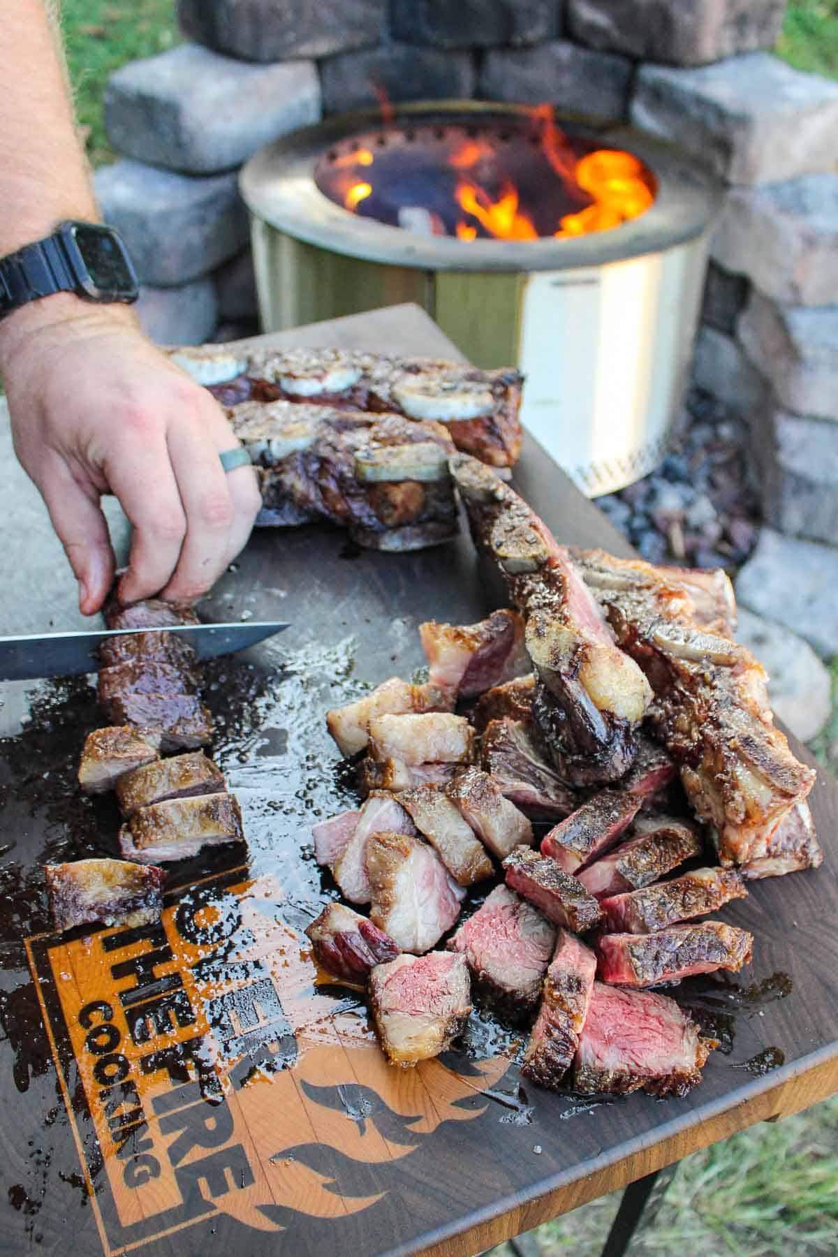 Steak getting sliced by Derek Wolf on a cutting board.