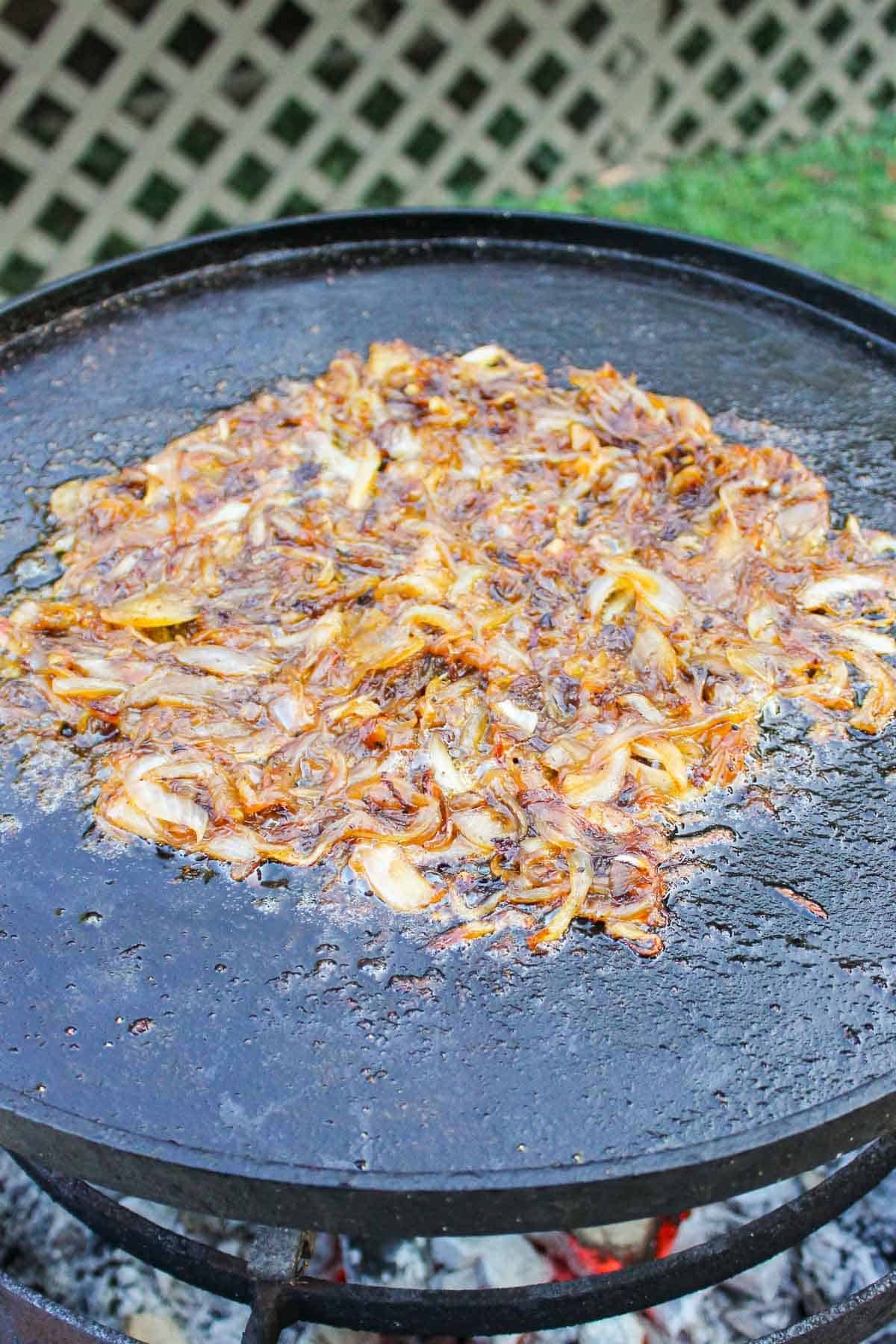 The onions as they brown on the skillet over the flames. 