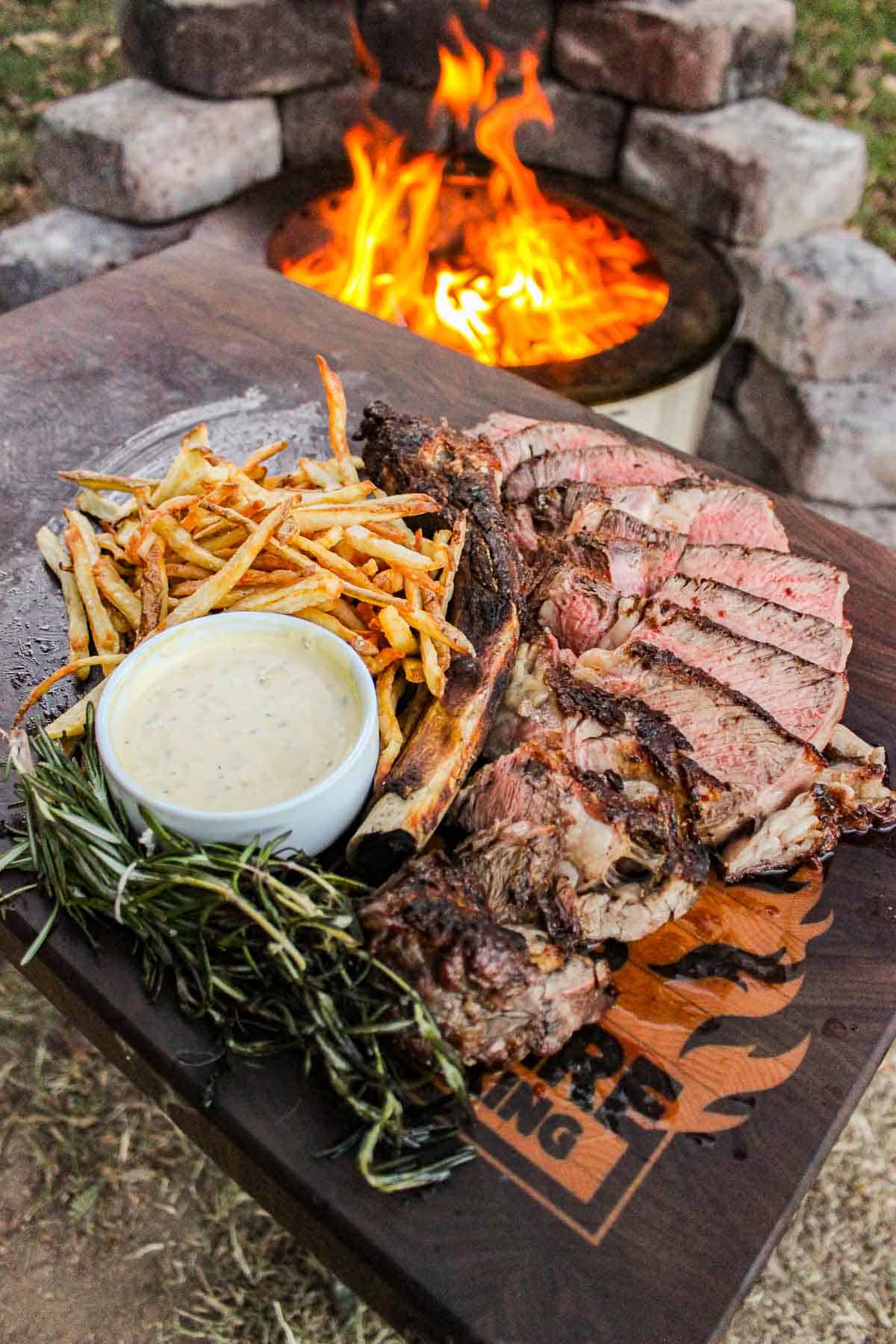The grilled ribeye with beef tallow fries on a cutting board.