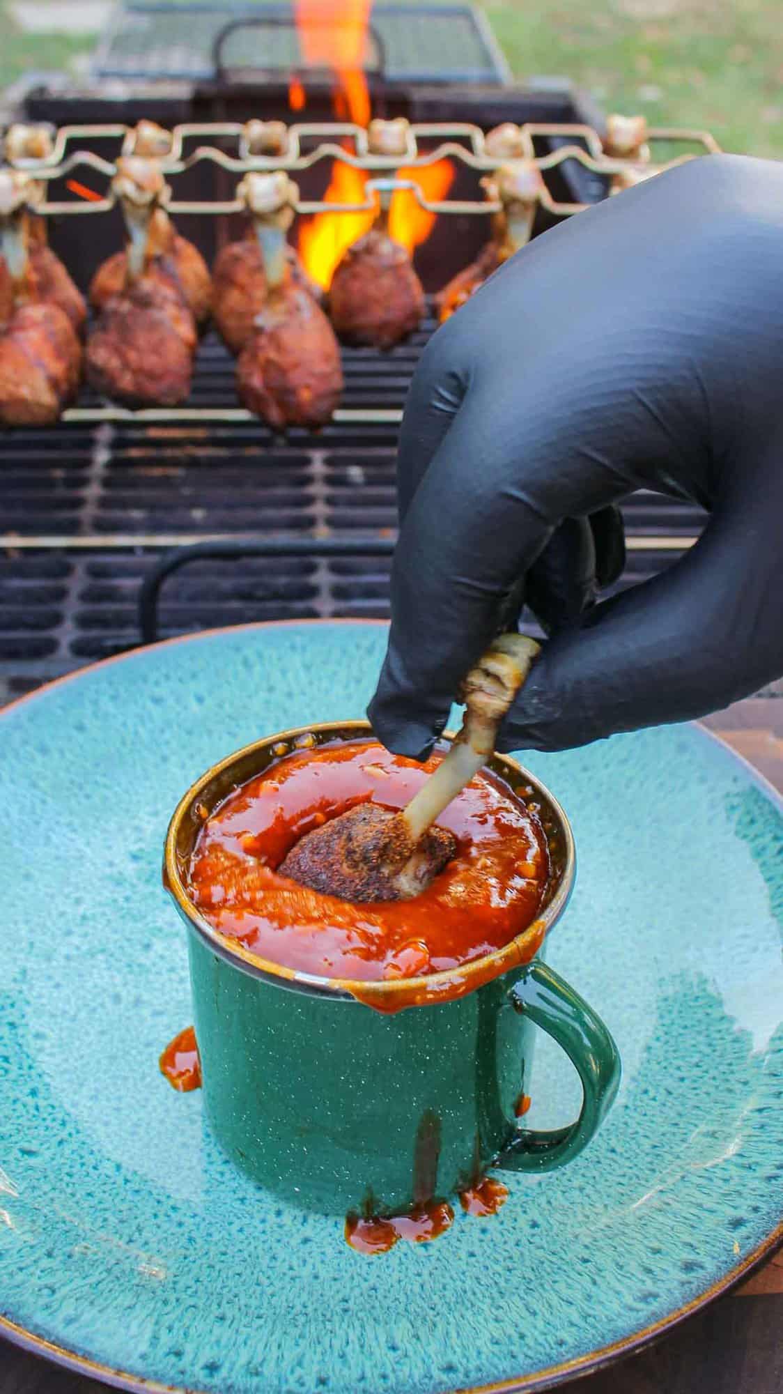 The chicken drumstick getting dunked in its sauce.