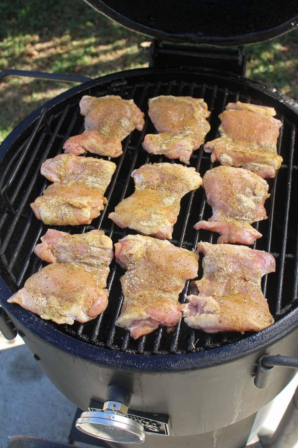 The raw chicken thighs getting placed on the smoker. 