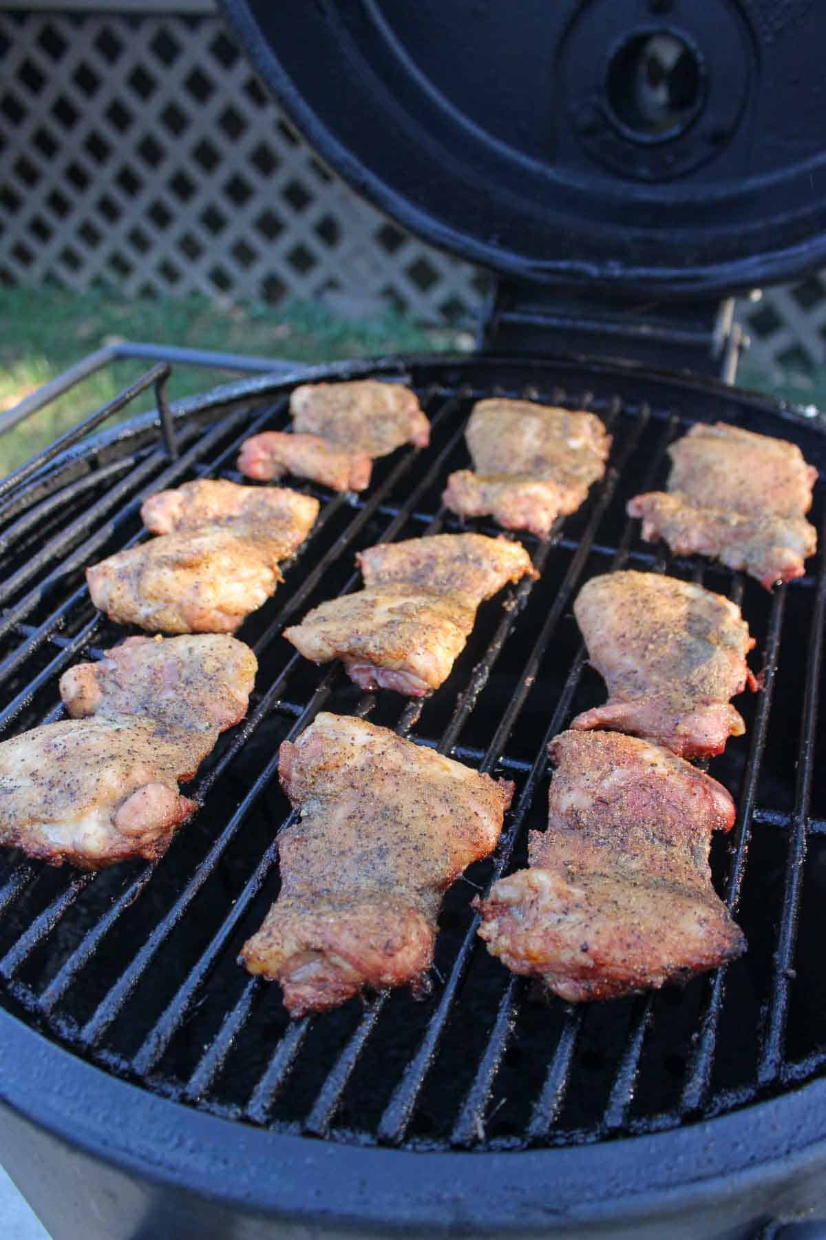 The cooked chicken thighs sitting on the smoker. 