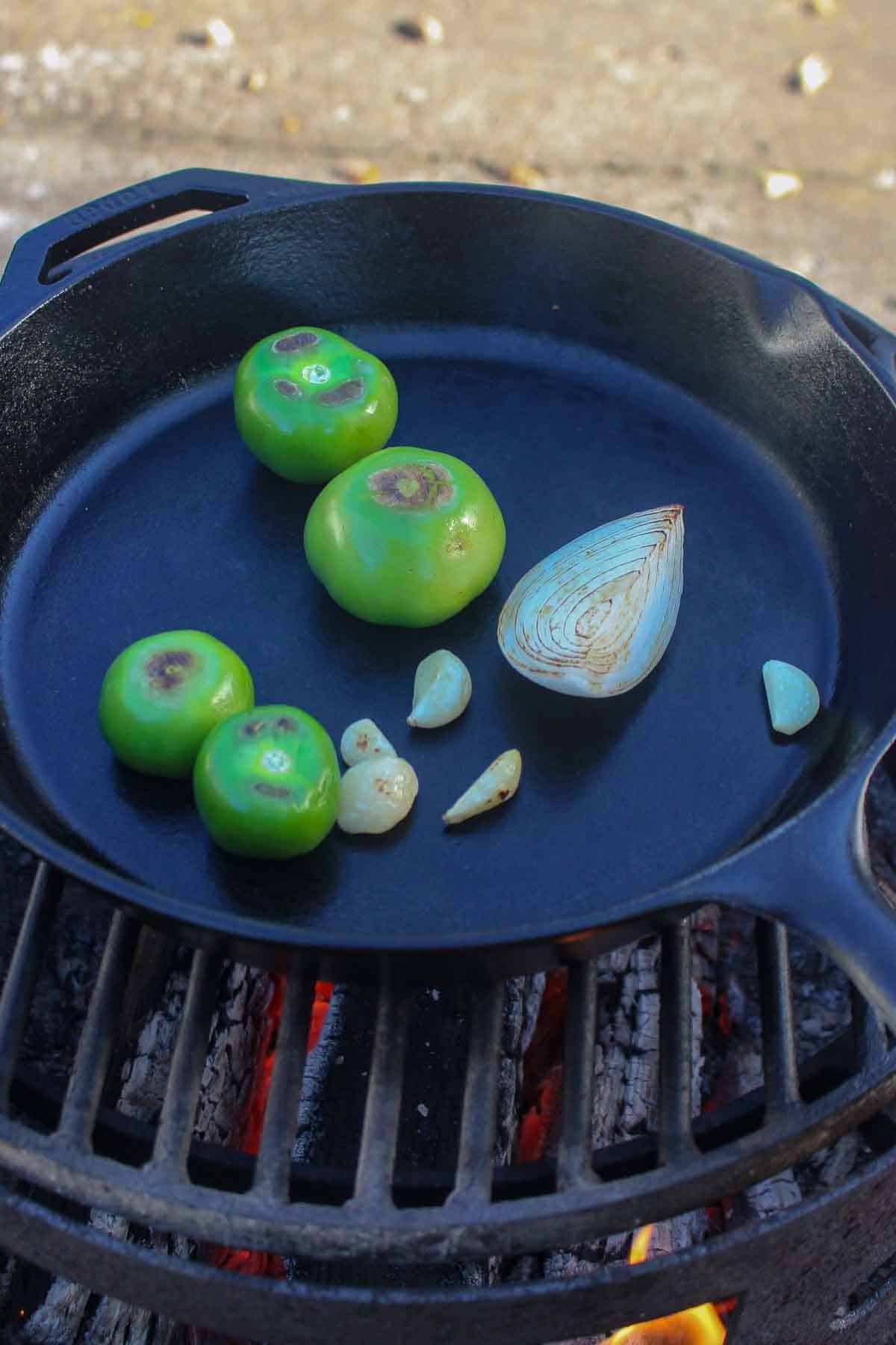 The tomatillos, onion and garlic charring in a cast iron skillet.