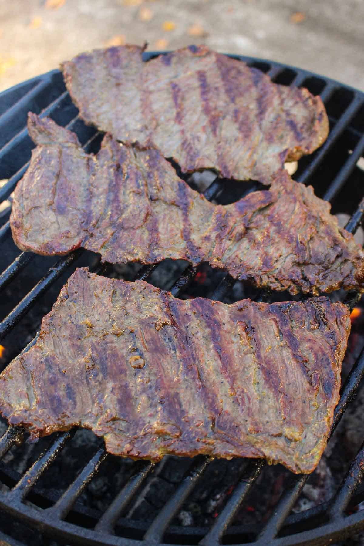 The grilled steak cooking on the grill.