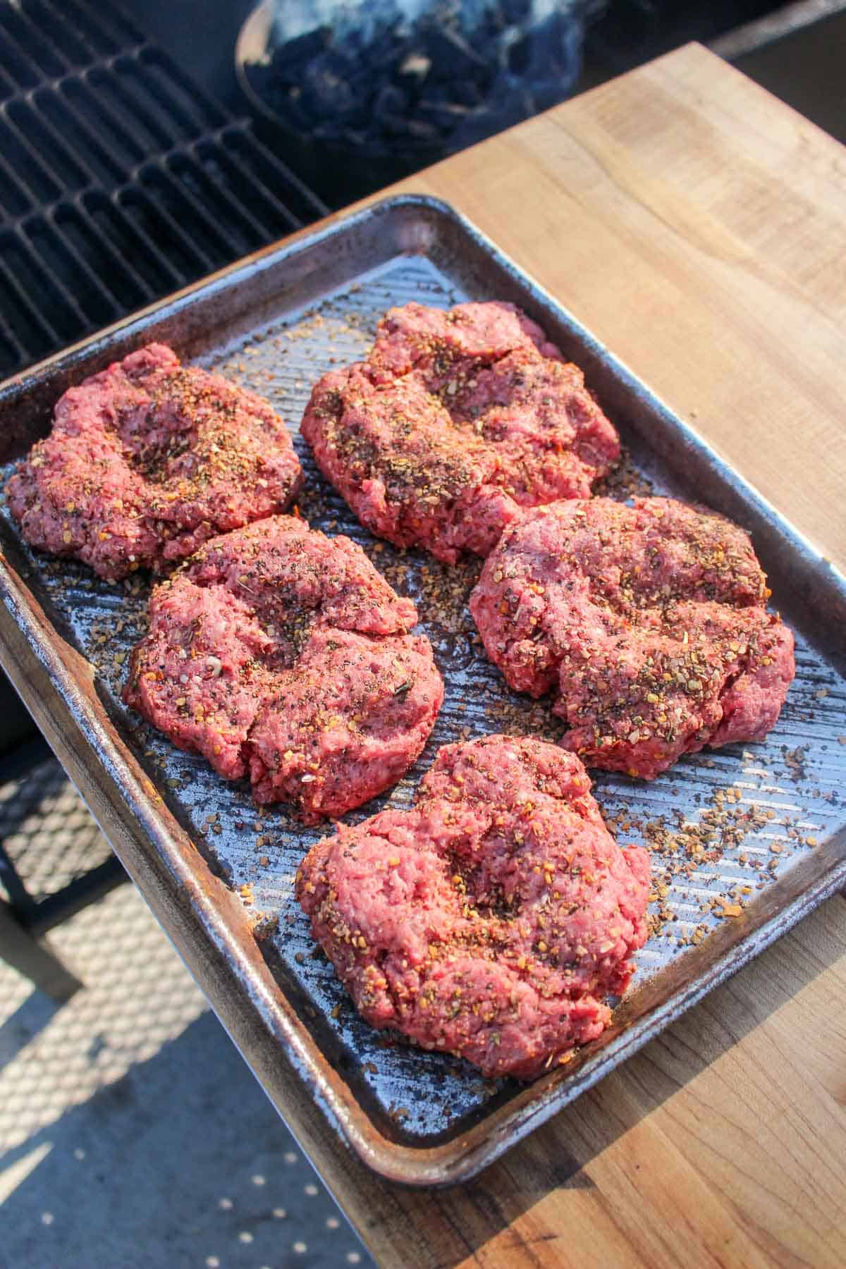 The seasoned burger patties before getting placed on the grill.