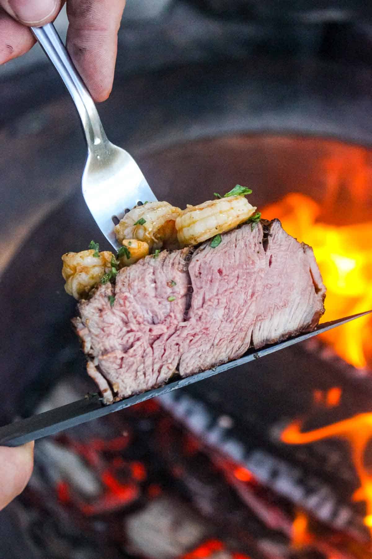 A close up shot of a sliced filet mignon with the garlic shrimp on top.