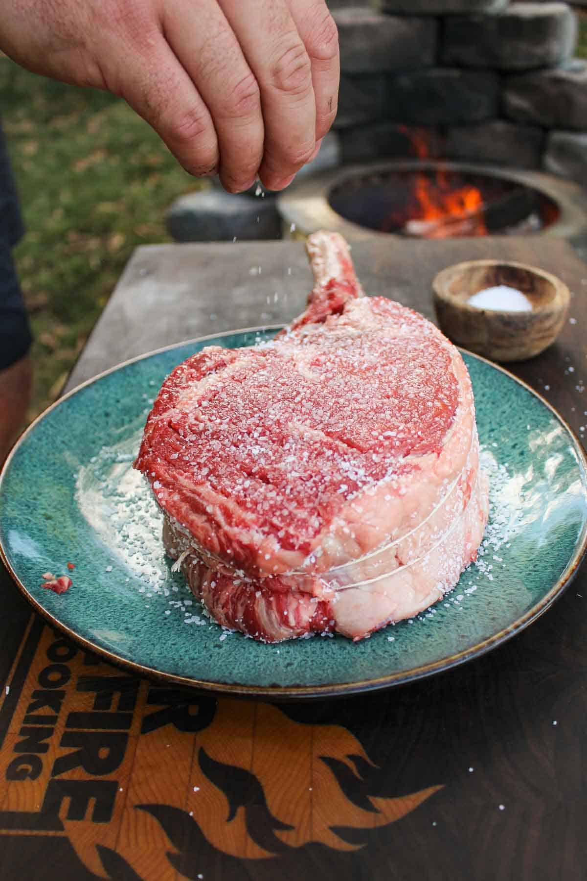 A steak getting salted.