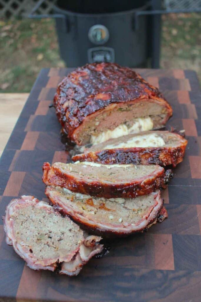 Cheese Stuffed Smoke Meatloaf sliced and sitting on a cutting board.