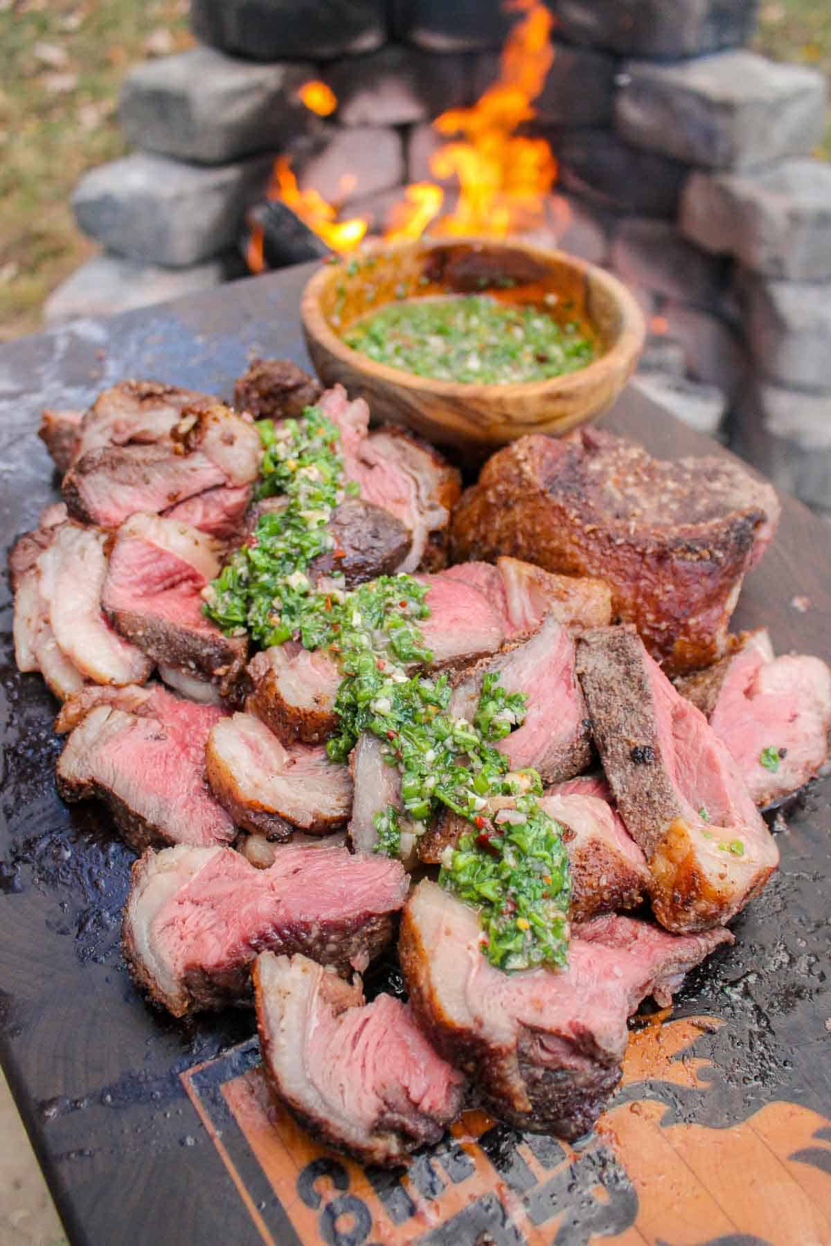 Skewered Picanha with Bone Marrow Chimichurri served on a cutting board.