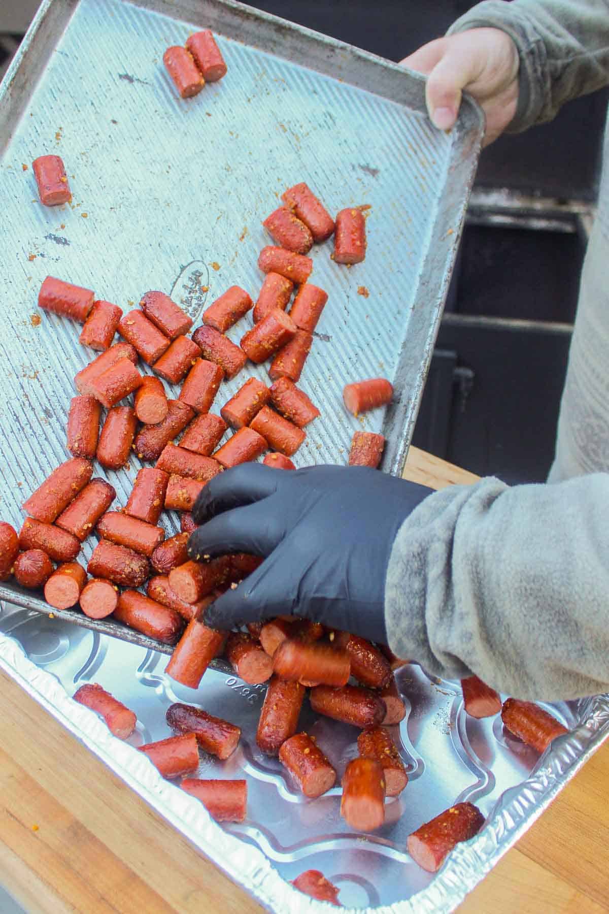 Hot dogs getting poured into an aluminum pan.