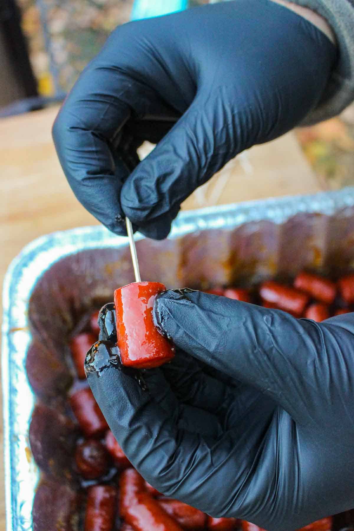 Placing a toothpick in one of the hot dog burnt ends.