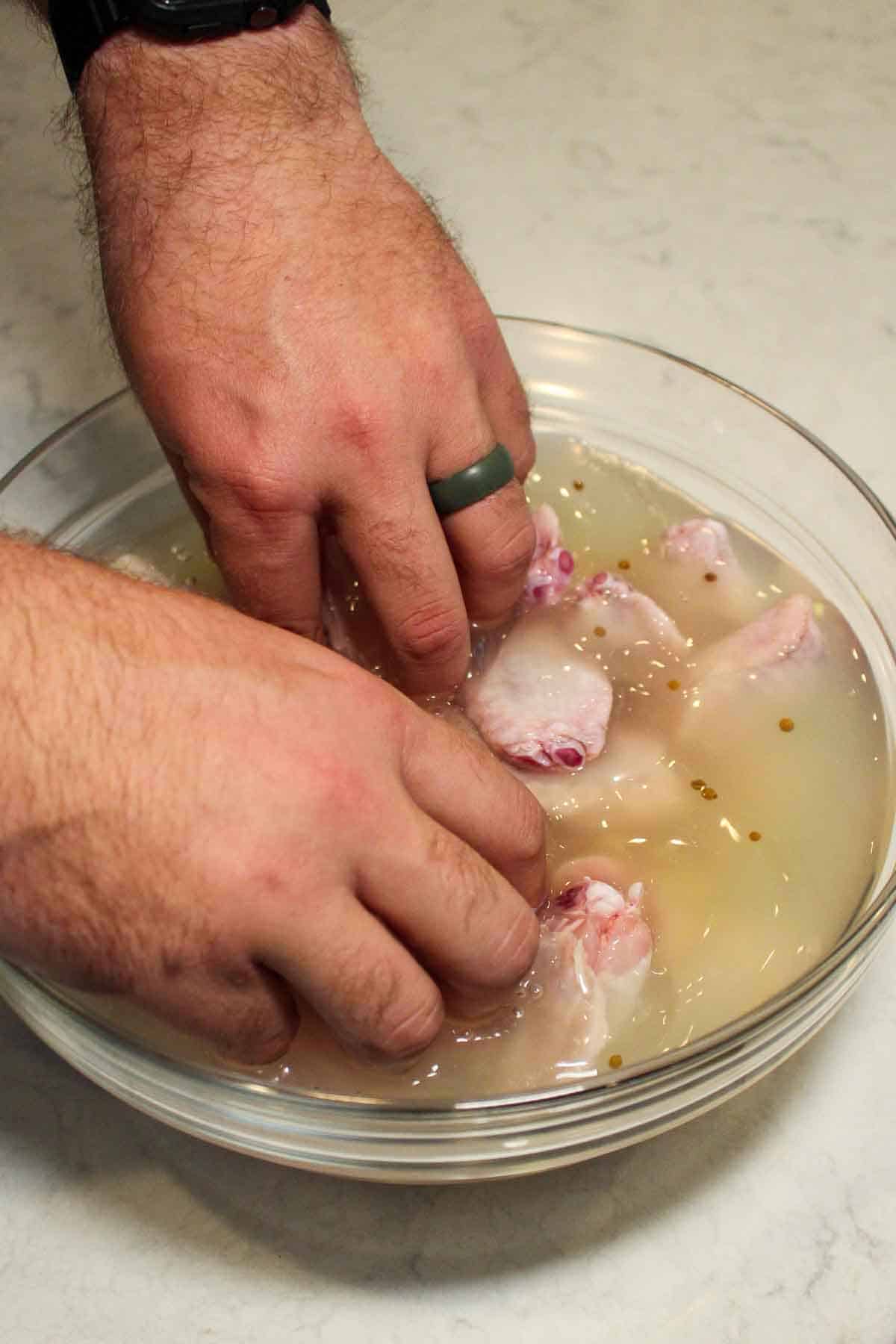 Adding the chicken wings to the pickle brine.