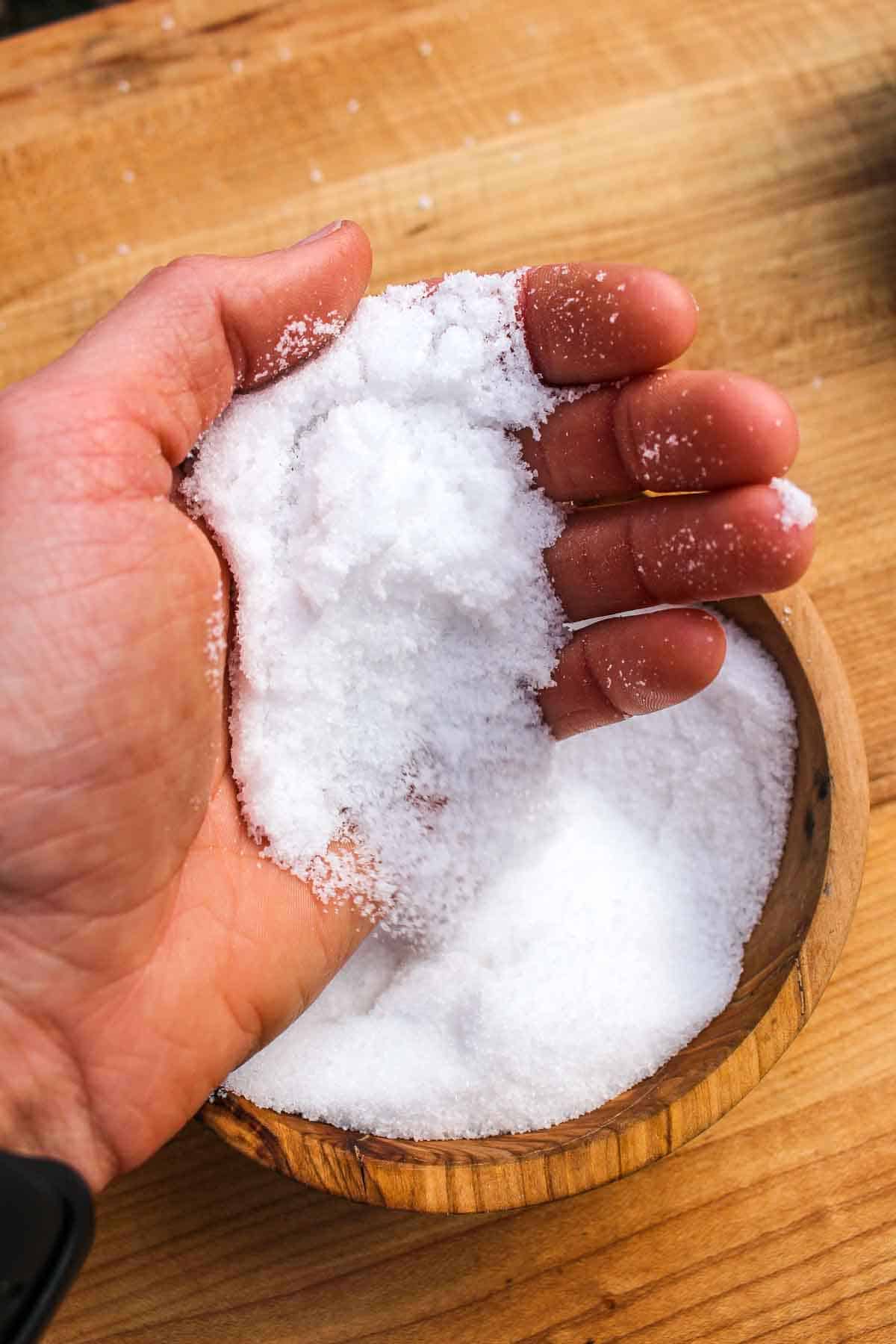 Sea Salt falling from a hand into a bowl below.