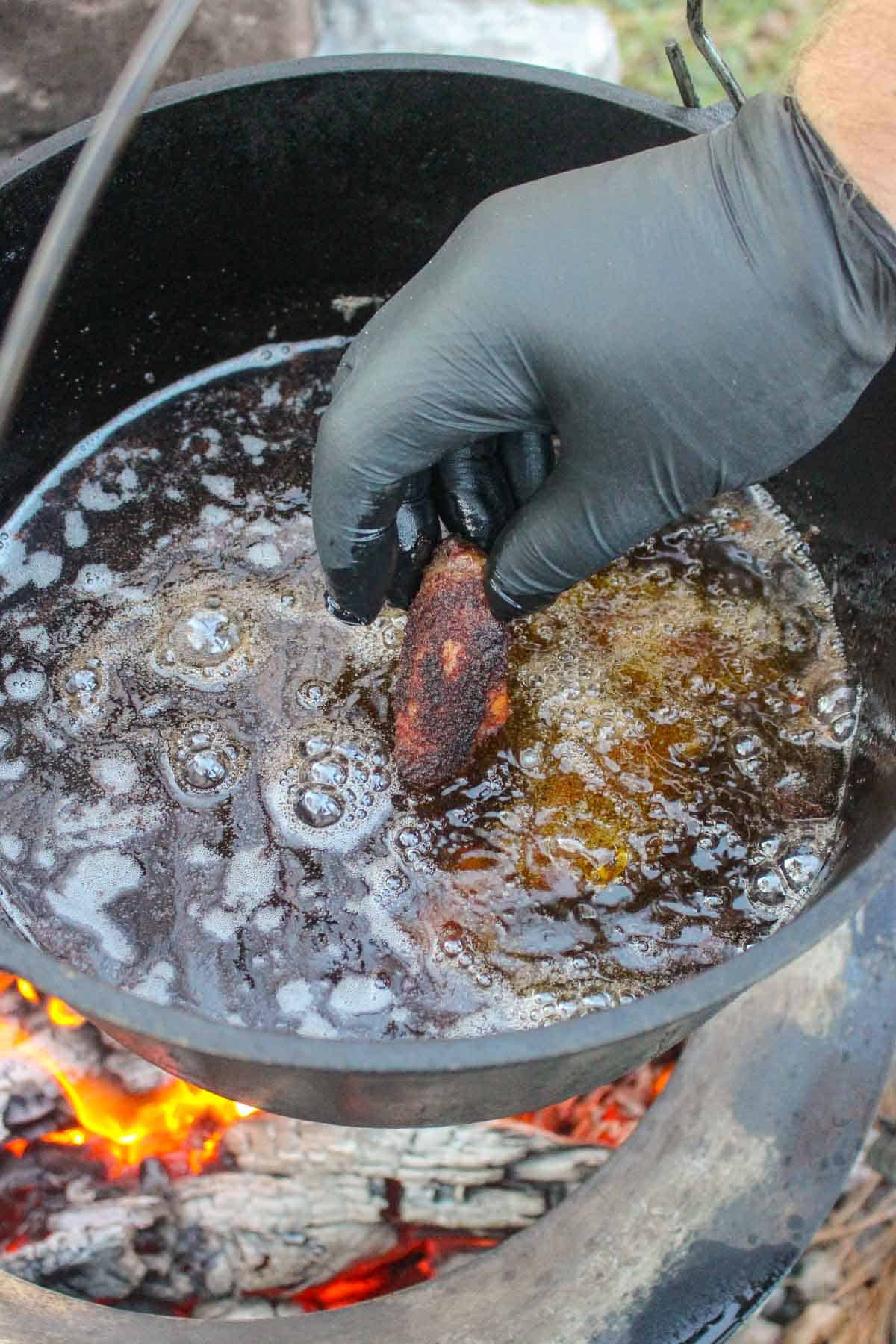 Adding a chicken wing to the frying oil.