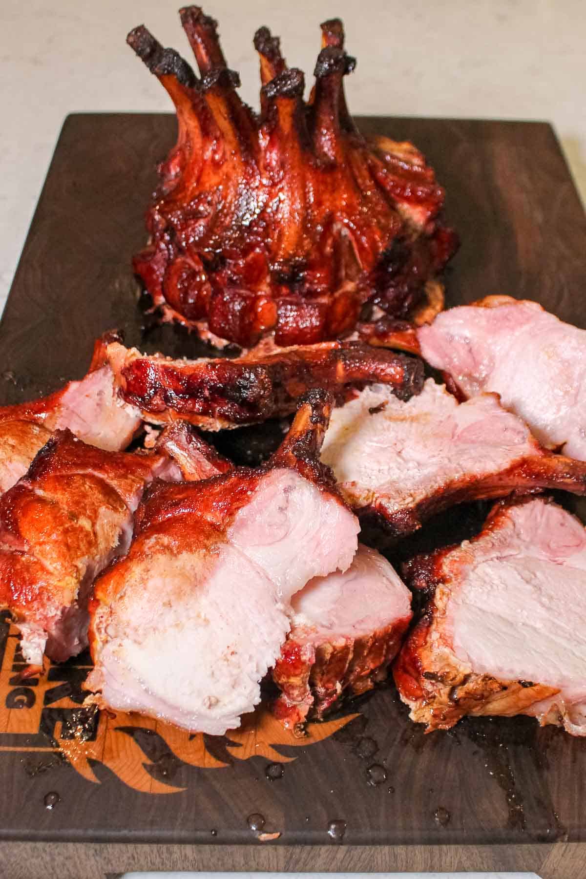 One pork crown with multiple slices of pork sitting on a cutting board. 