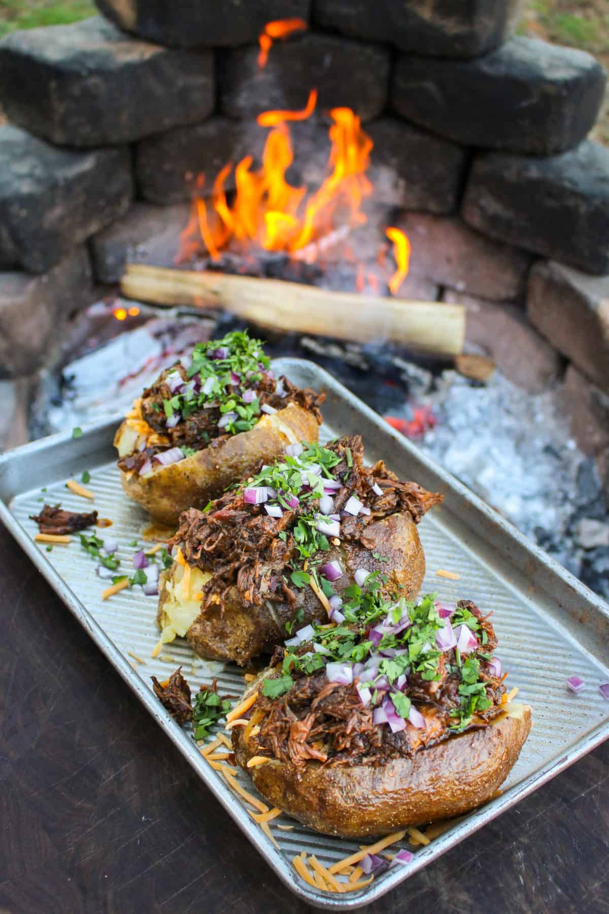 Birria Baked Potato assembled and sitting in front of the fire.