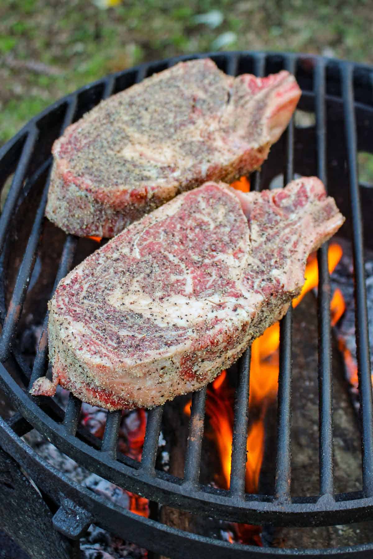 The raw Cowboy Steaks getting placed on the grill.