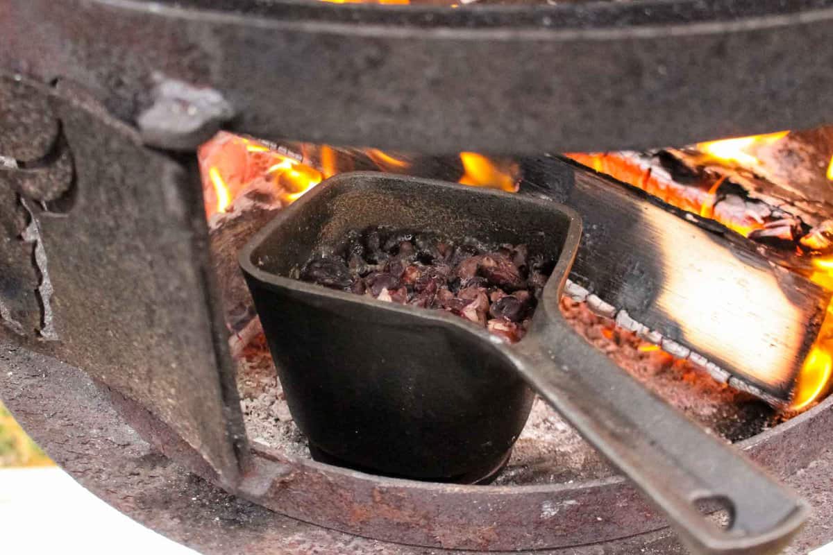 The beans cooking in a cast iron next to the flames. 
