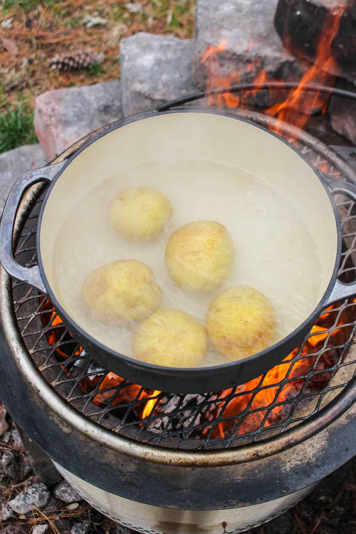 The whole potatoes in boiling water on the grill.