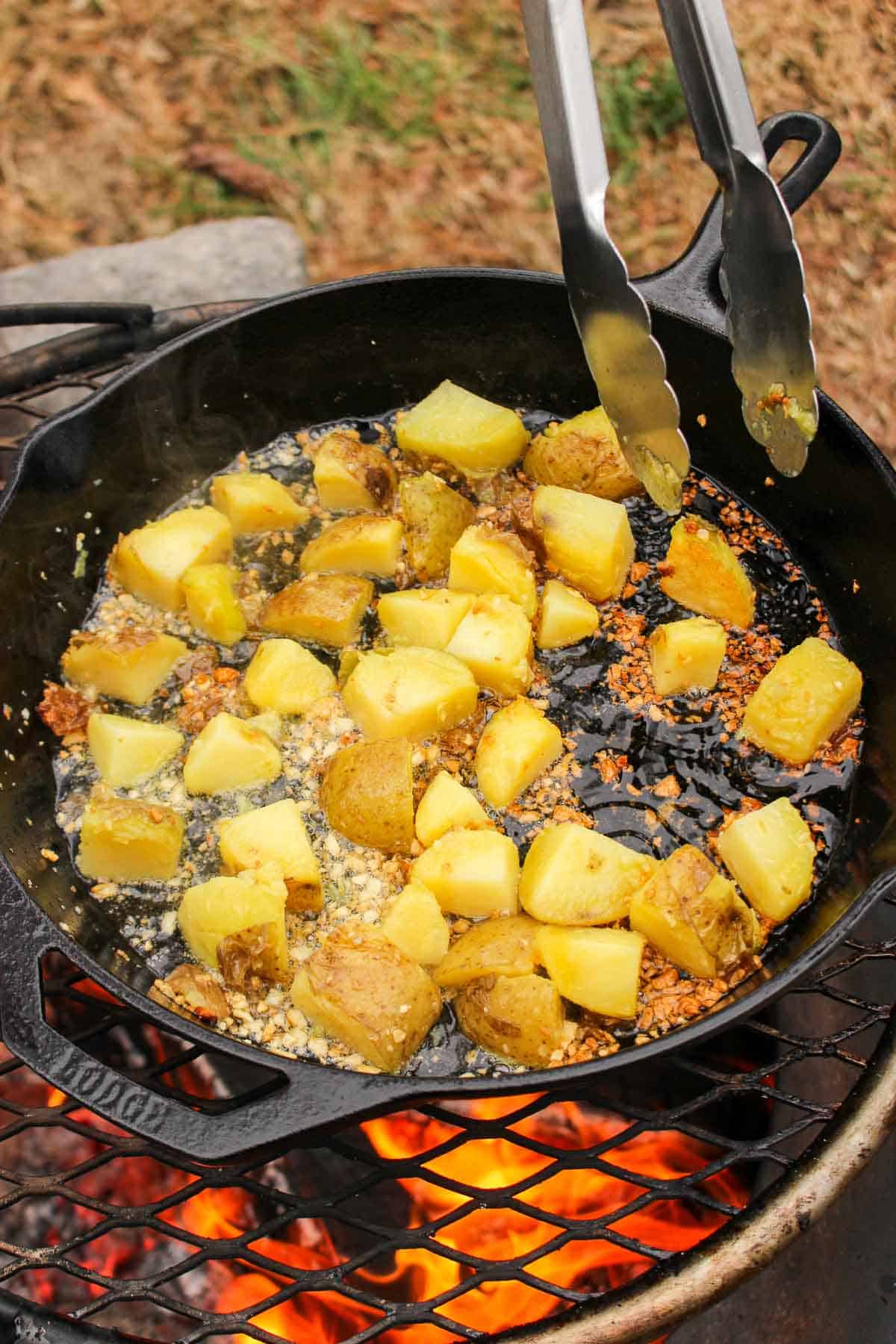 The potatoes now sliced and in a skillet with roasting garlic.