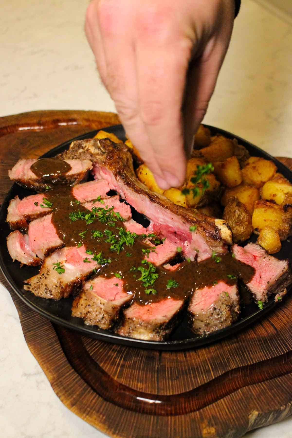 Garnishing the Pan Seared Steaks with Crispy Potatoes before serving.