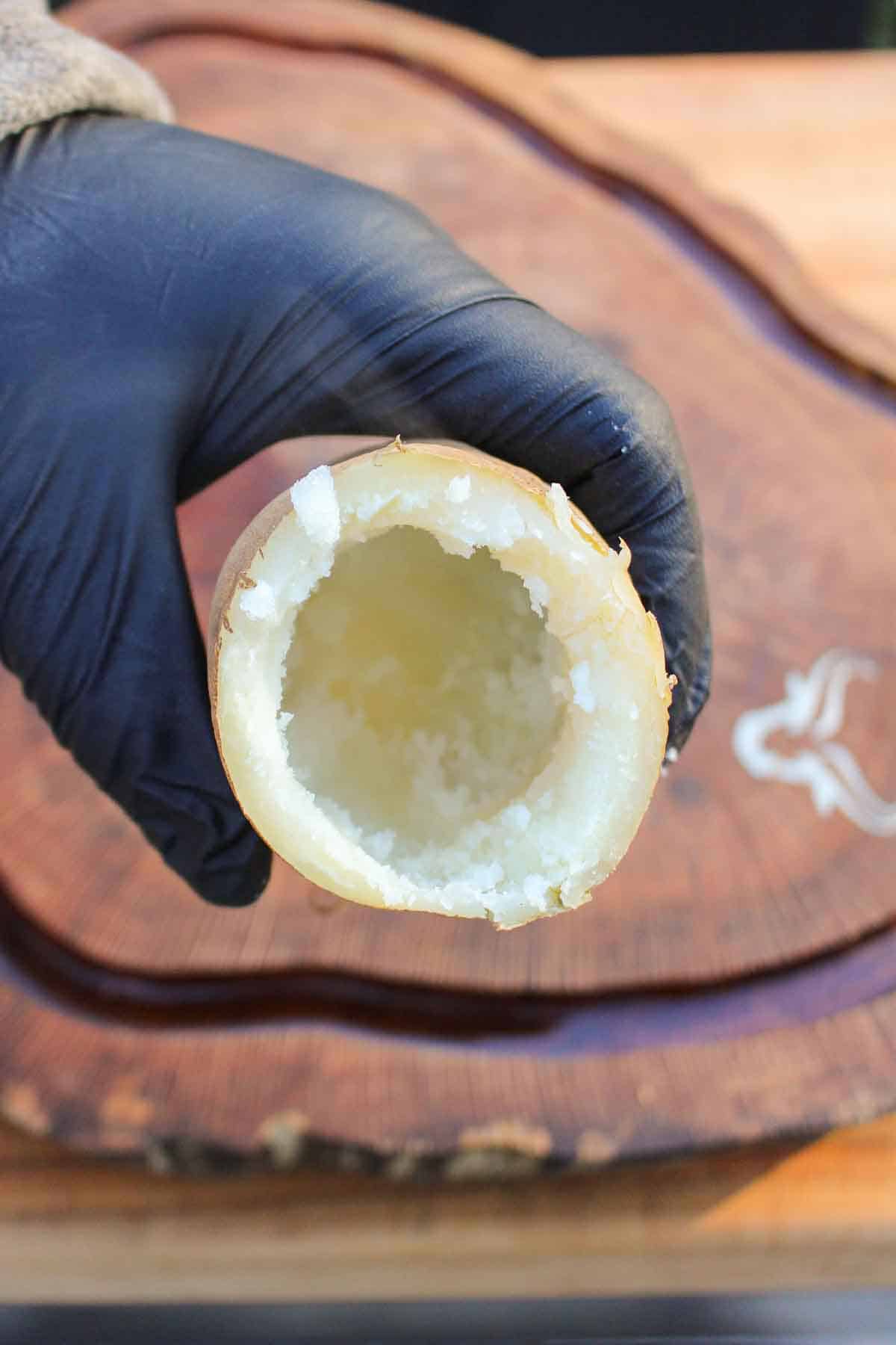 Showing the inside of a hollowed potato to the camera.