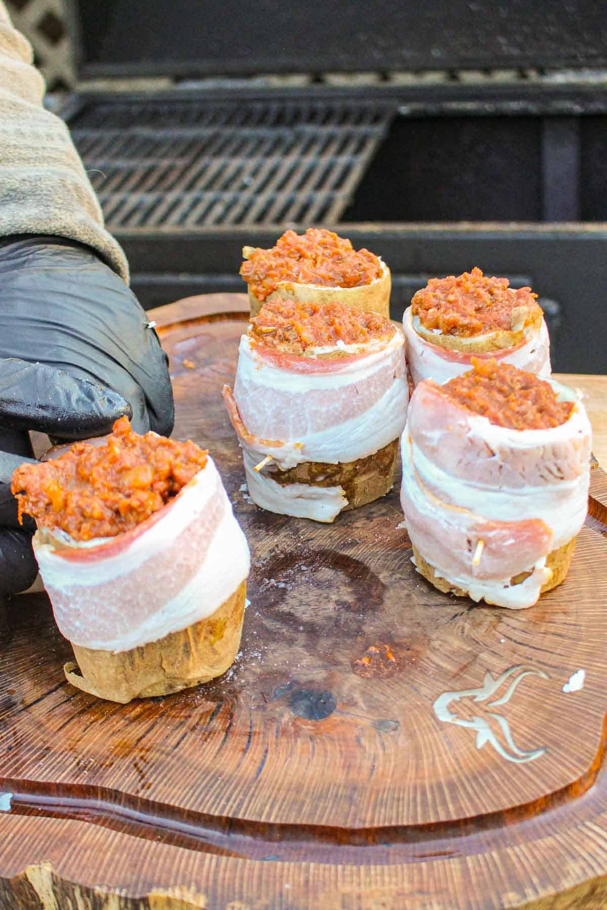Wrapping the Chili Cheese Potato Volcanoes with bacon.