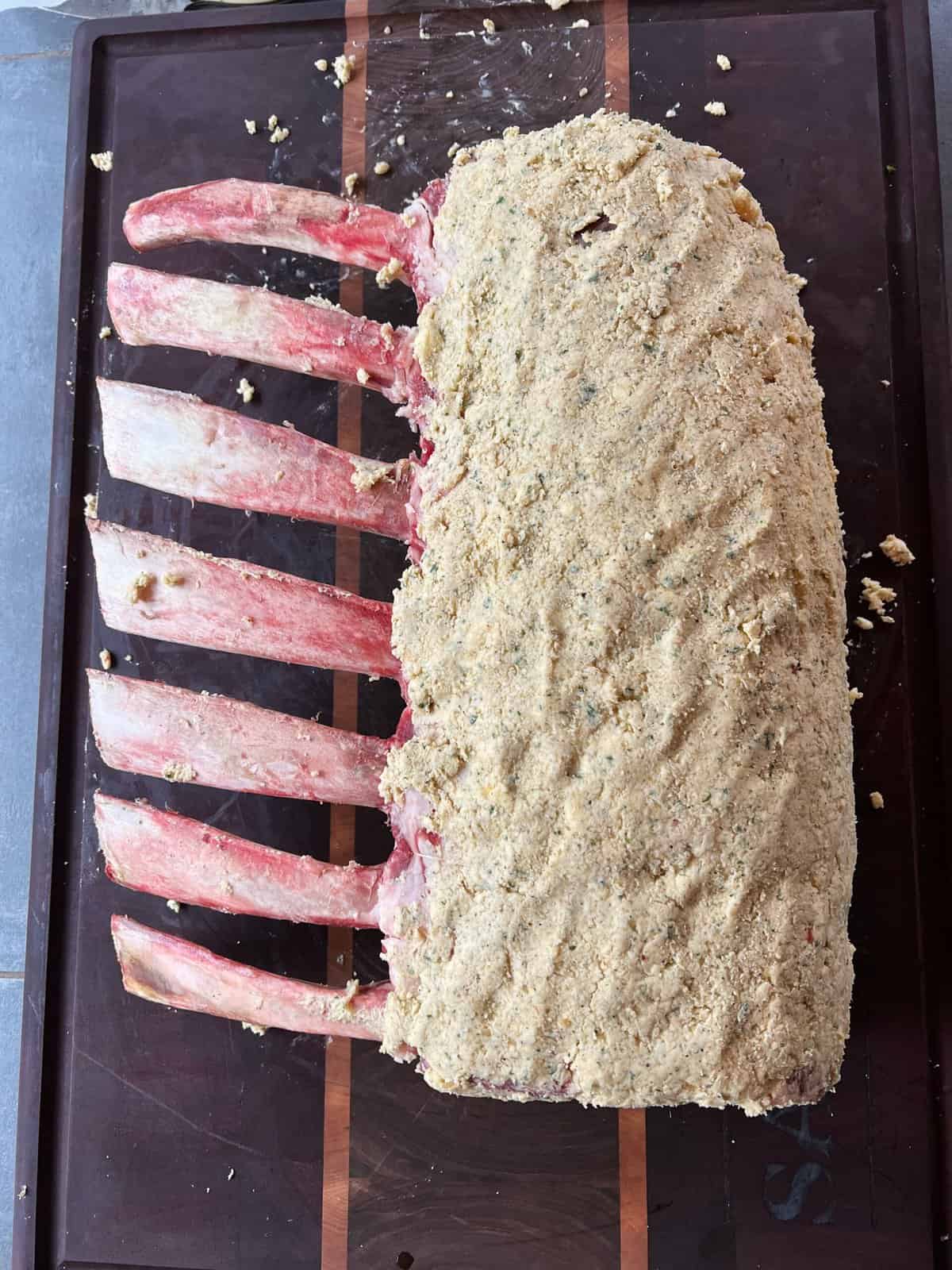 The raw roast on a cutting board covered in the compound butter.