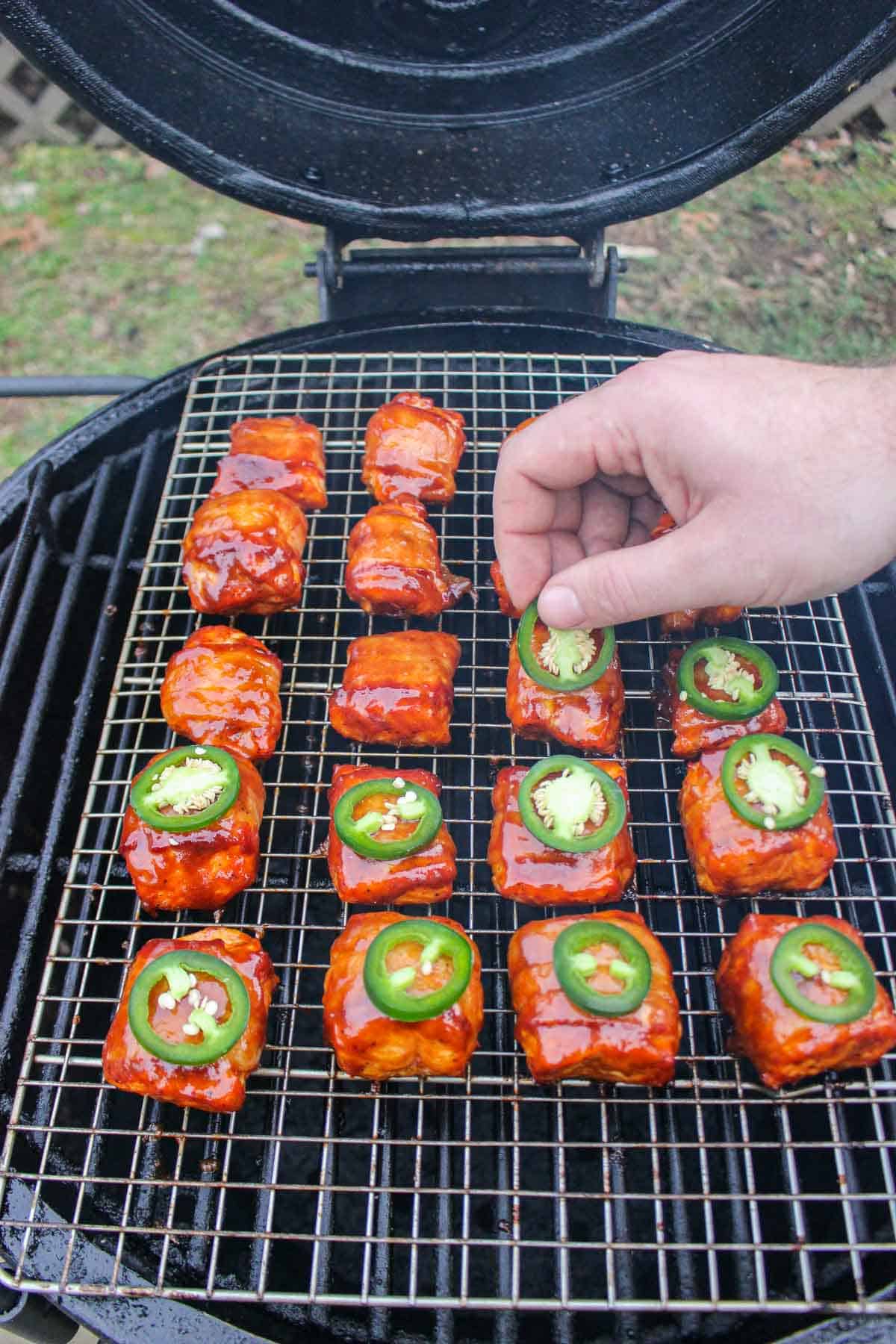 Adding a sliced jalapeño to the top of each salmon bite.