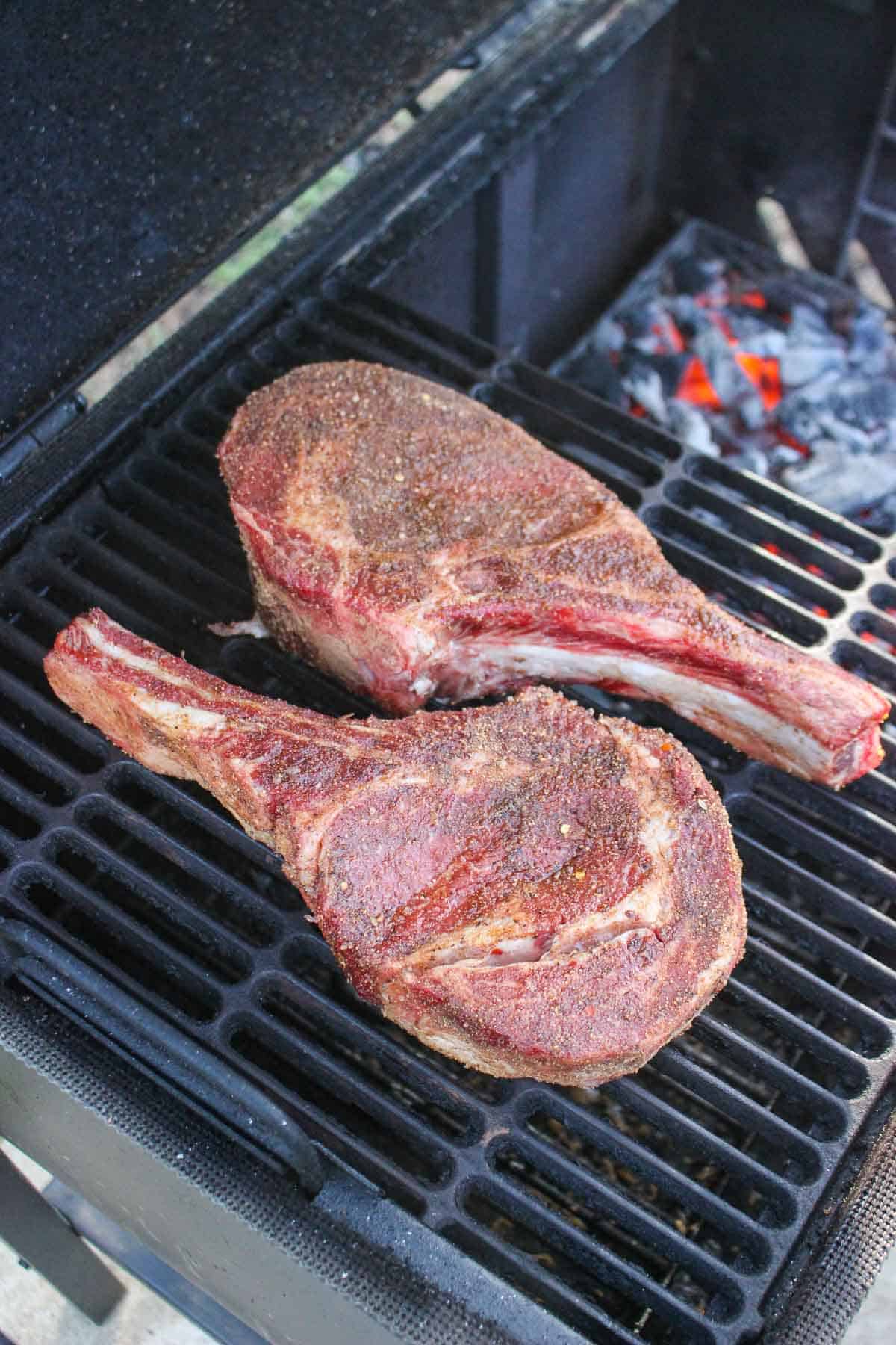 The raw steaks being placed the grill.