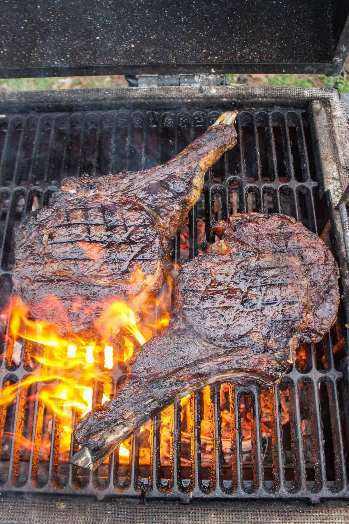 The grilled ribeyes being seared directly over the flames.