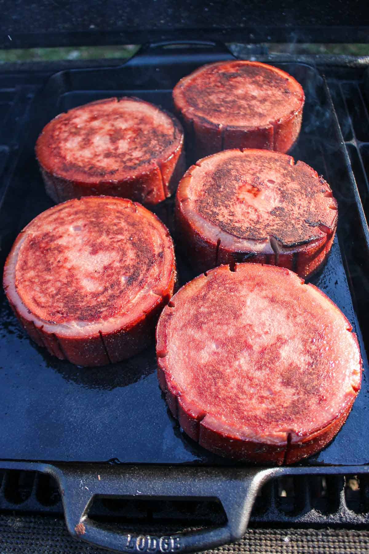 The bologna slices after being flipped on the grill.