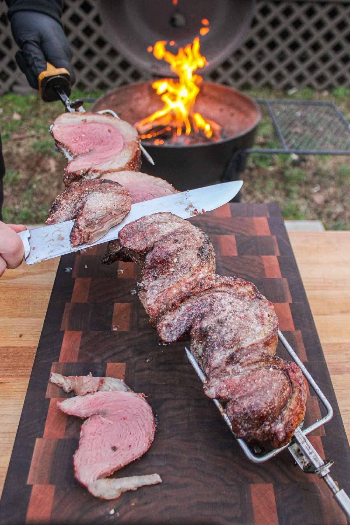 Slicing the rotisserie picanha off the skewer.