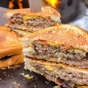 Oklahoma Onion Patty Melt sliced and sitting on a serving platter.