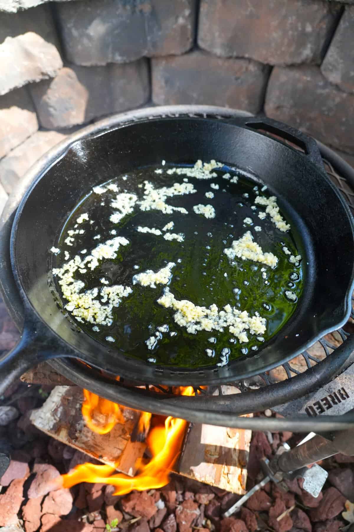 Sauteeing garlic in a cast iron skillet over the grill