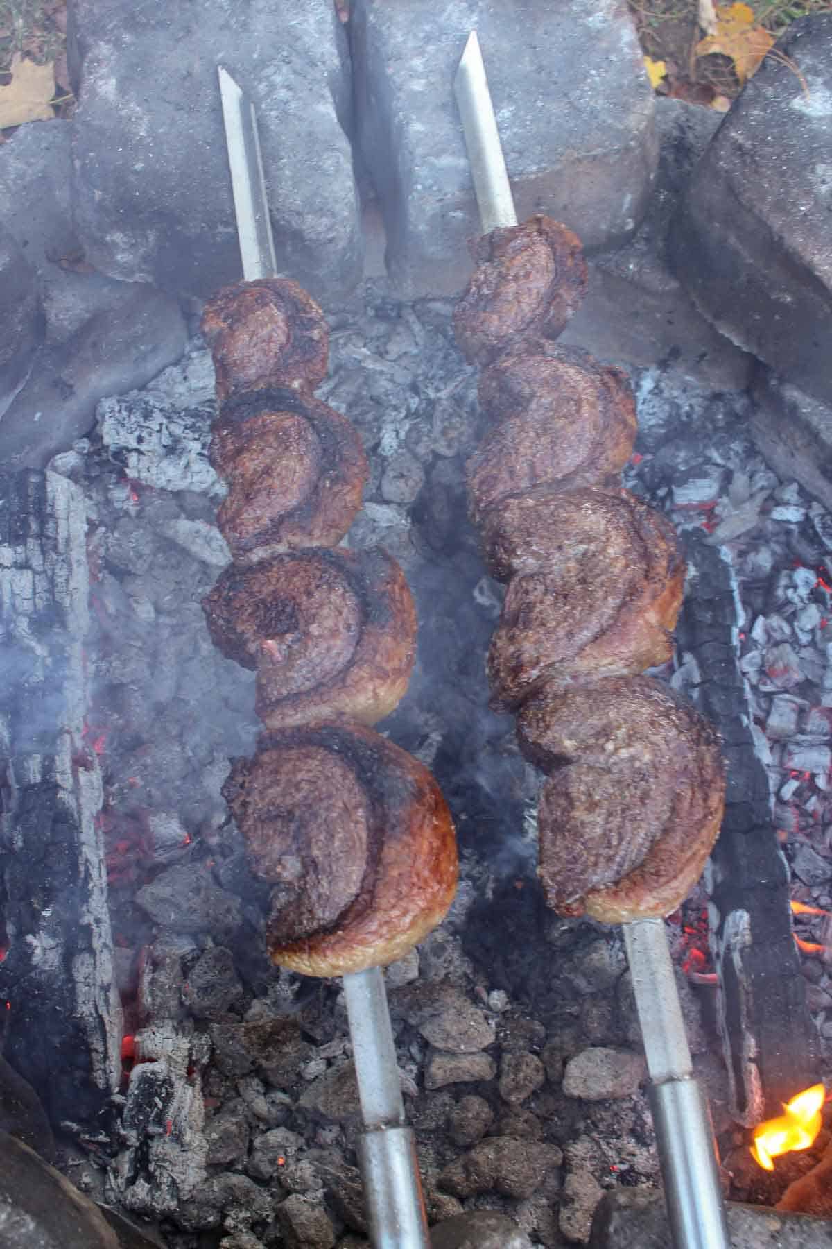 A shot of the skewered picanha cooking over the coals.