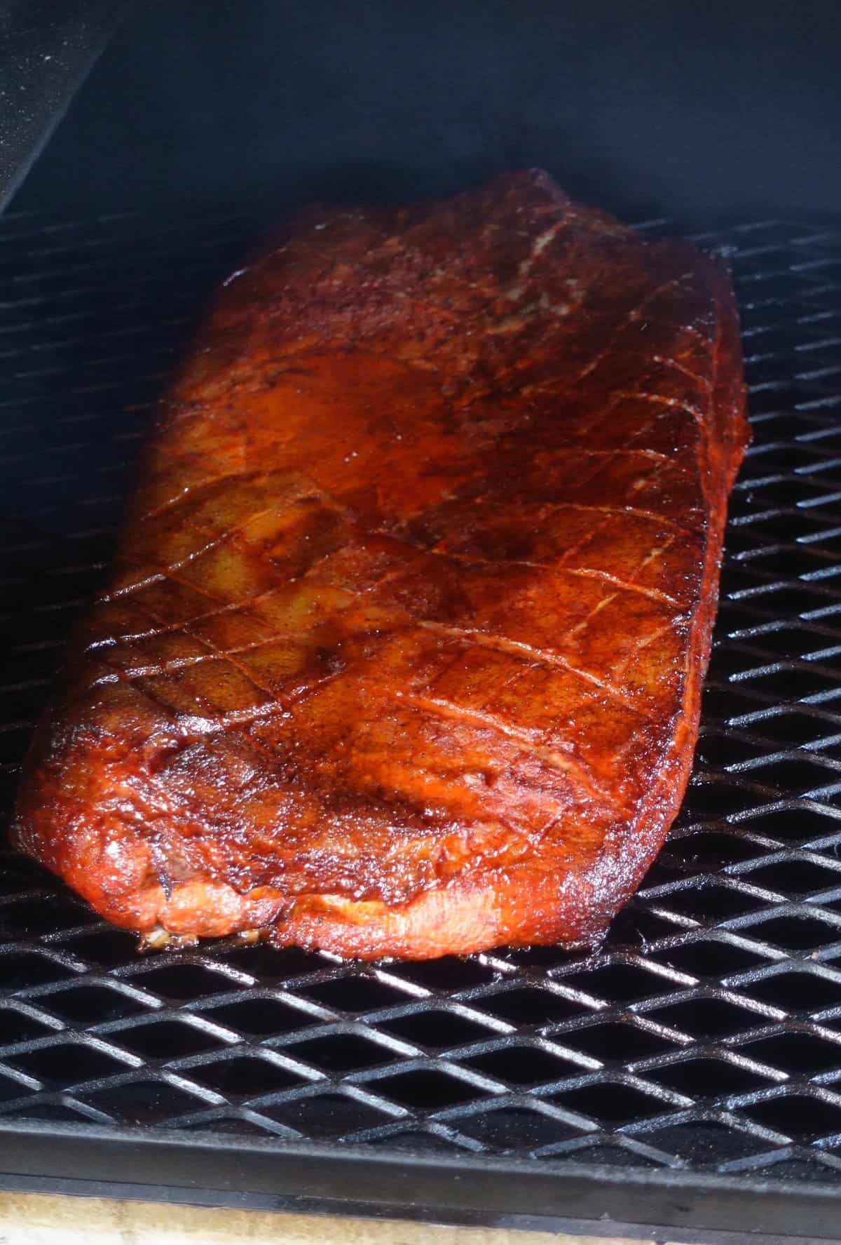 The pork belly in the smoker as it cooks.