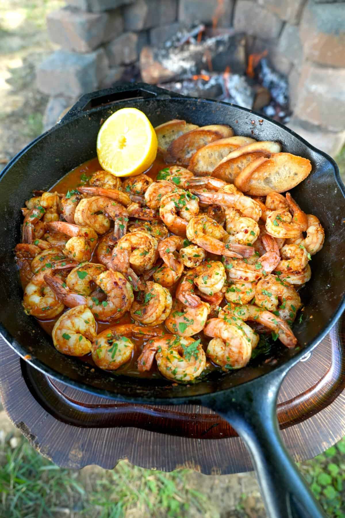 Finished and cooked Spanish garlic shrimp in a cast iron skillet, with a half lemon in the corner