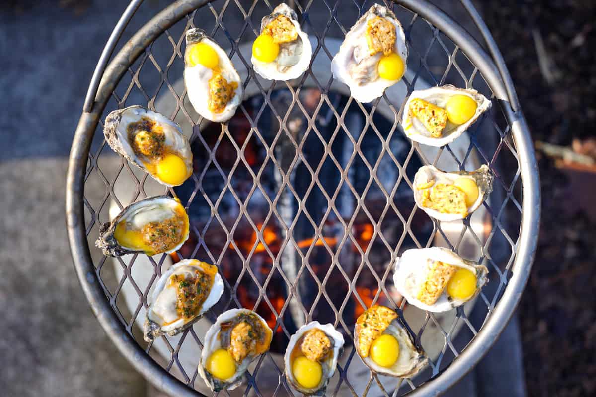 The oysters with butter and quail eggs cooking on the grill.