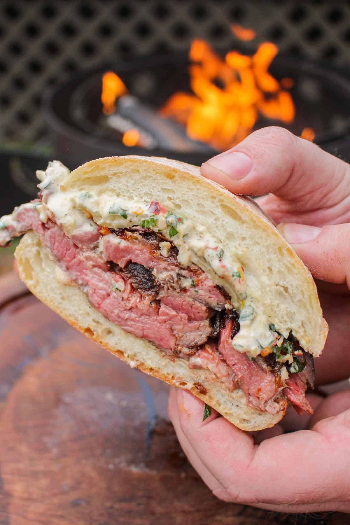 Chimichurrie Steak Sandwich being held close to the camera to show the assembly of the sandwich.