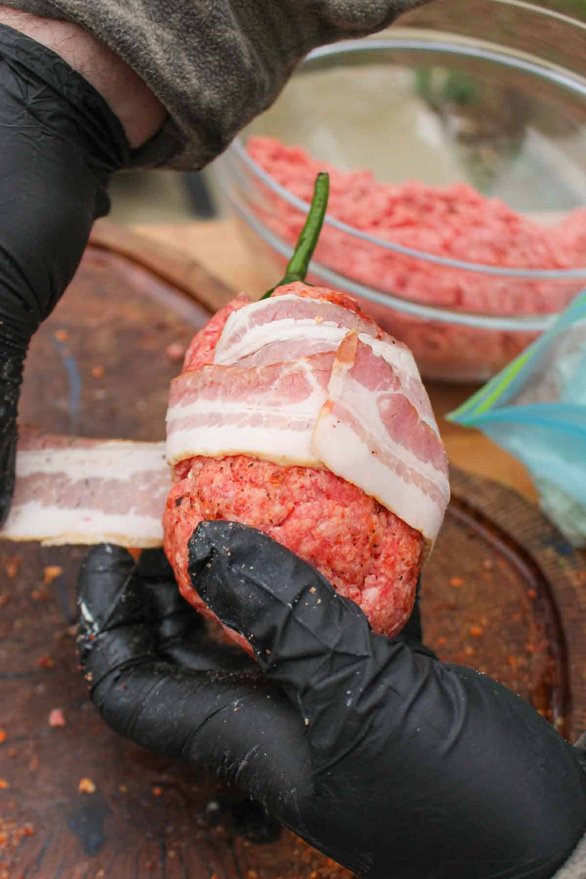 Wrapping the beef armadillo egg in bacon.
